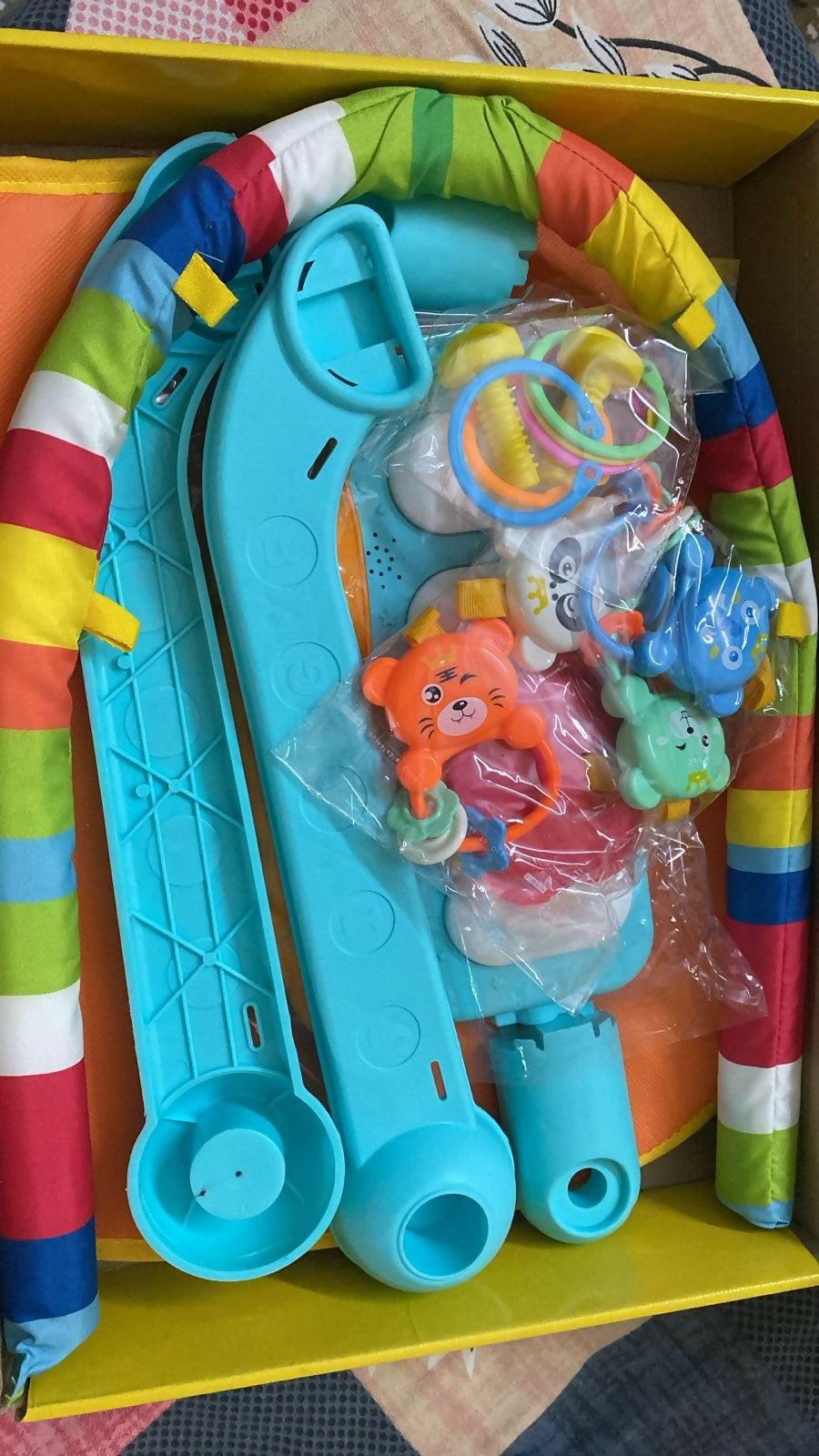 Colorful baby play gym with toys on a yellow surface