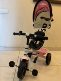 Pink and black tricycle with a mirror on a tiled floor.