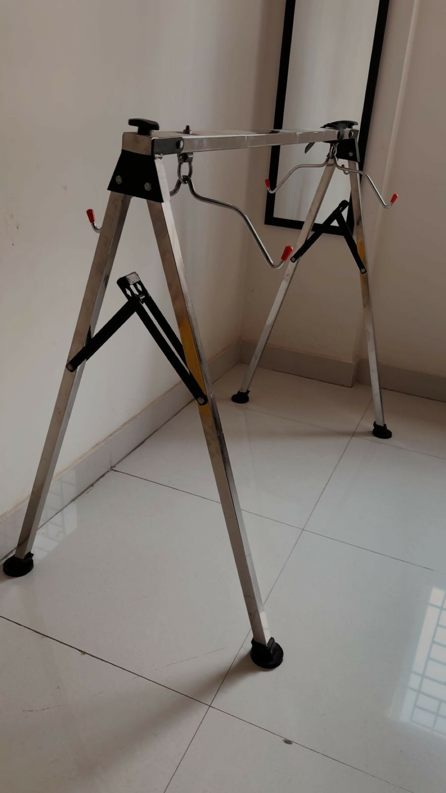 Metal workbench stand on a tiled floor with a white wall background