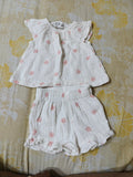 White children's outfit with floral pattern on a yellow floral background