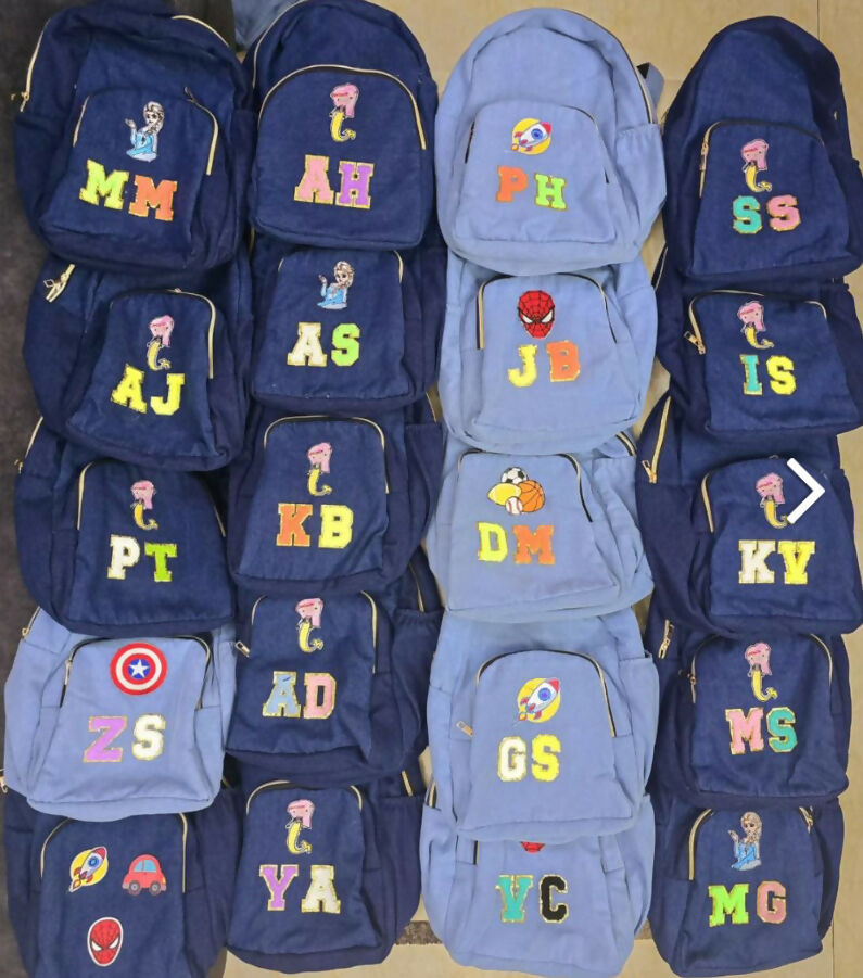 Collection of blue backpacks with colorful letters and symbols on a beige background