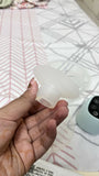 Hand holding a small white object against a patterned fabric background
