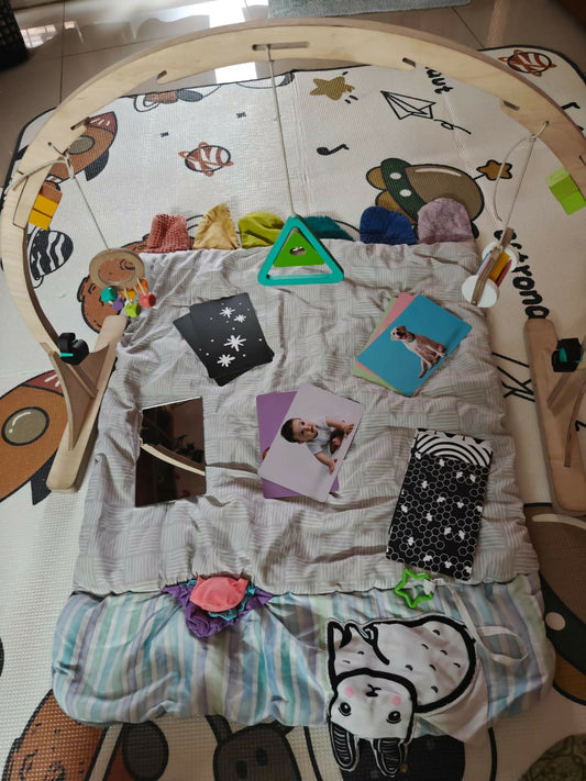 Play mat with various items including cards and toys on a wooden floor.