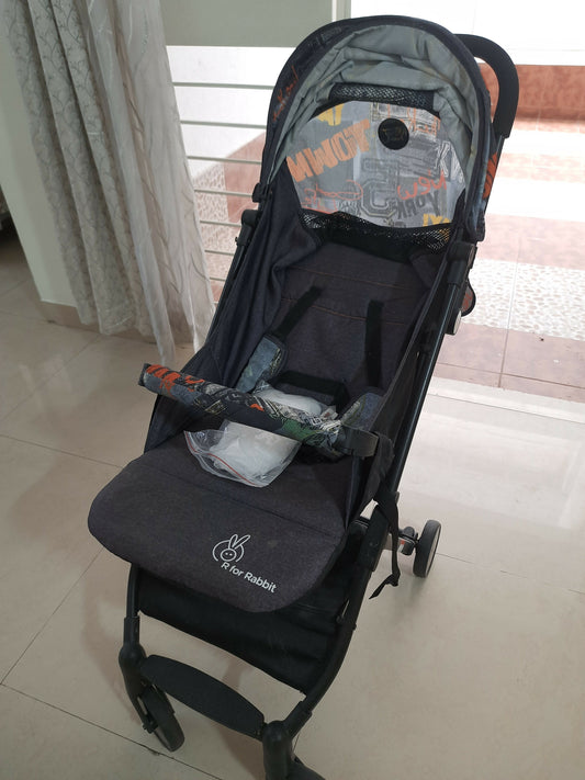 Black baby stroller with colorful design on a tiled floor