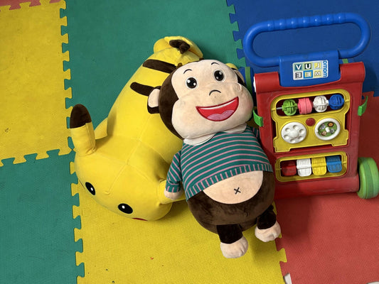 Plush monkey toy with a yellow animal toy and a colorful toy walker 
