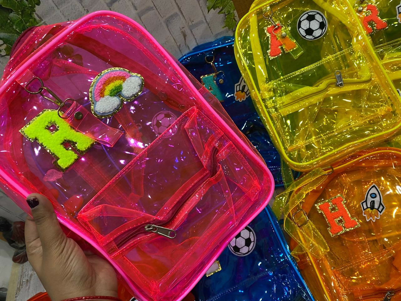 Colorful transparent bags with decorative charms and letters on a blurred background