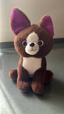 Plush toy dog with purple ears on a gray surface