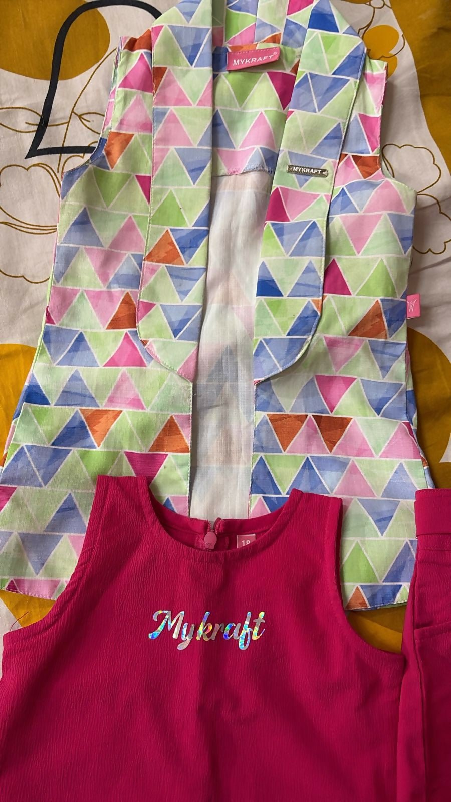 Colorful geometric-patterned jacket over a pink garment with 'My craft' text on a patterned background