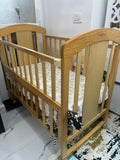 Wooden crib in a room with a white wall and tiled floor.