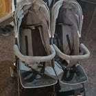 Double stroller with gray covers on a dark floor.