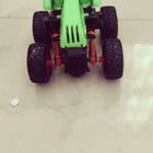 Green toy truck with large wheels on a light-colored floor