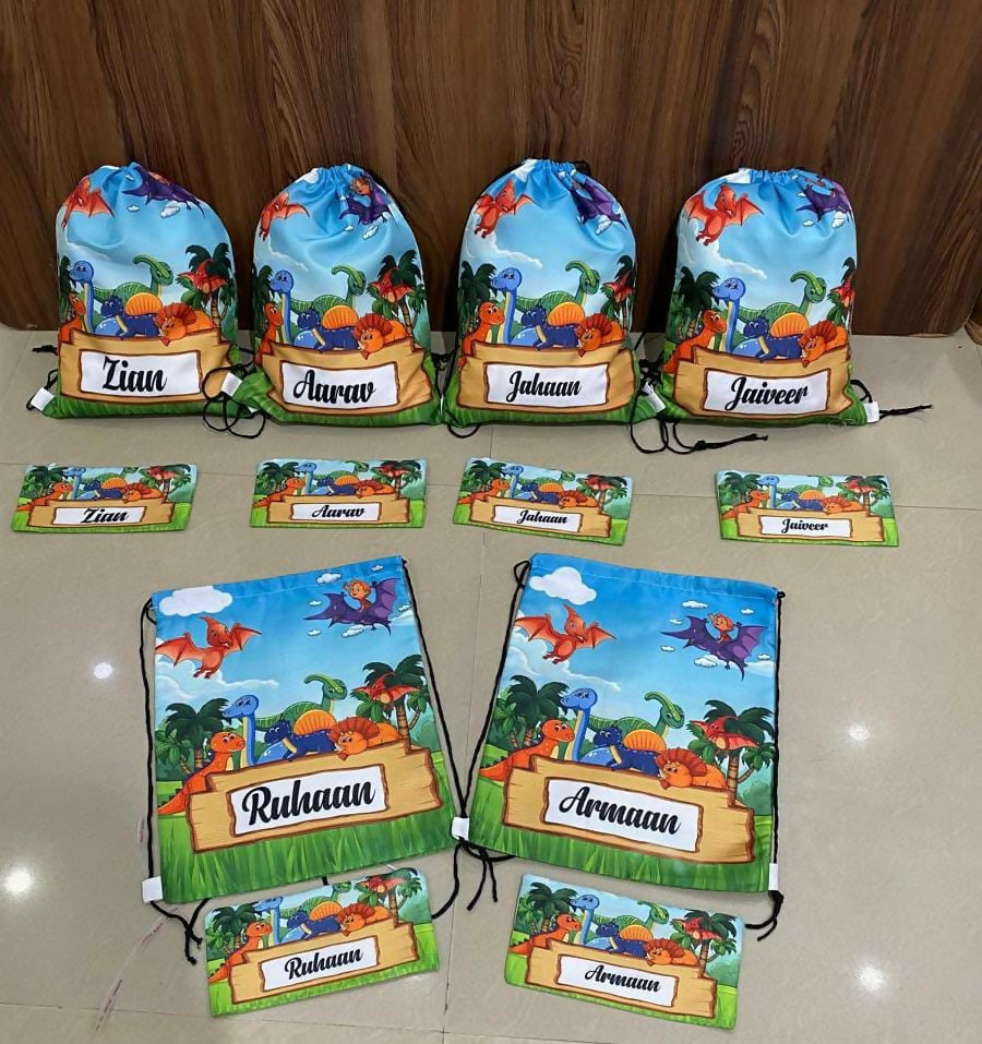 Set of drawstring bags with dinosaur designs and names on a beige surface.