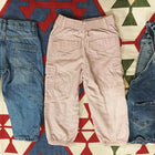 Three pairs of children's pants on a patterned rug