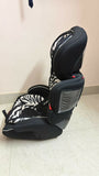 Black and gray car seat with zebra pattern on a tiled floor.