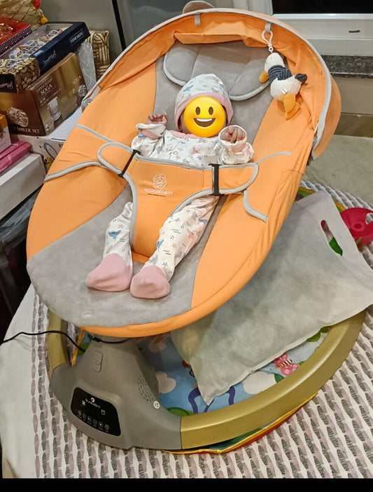 Baby in an orange and gray baby bouncer with a smiling emoji face toy.