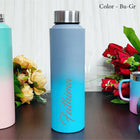 Gradient water bottle with floral arrangement on a wooden surface